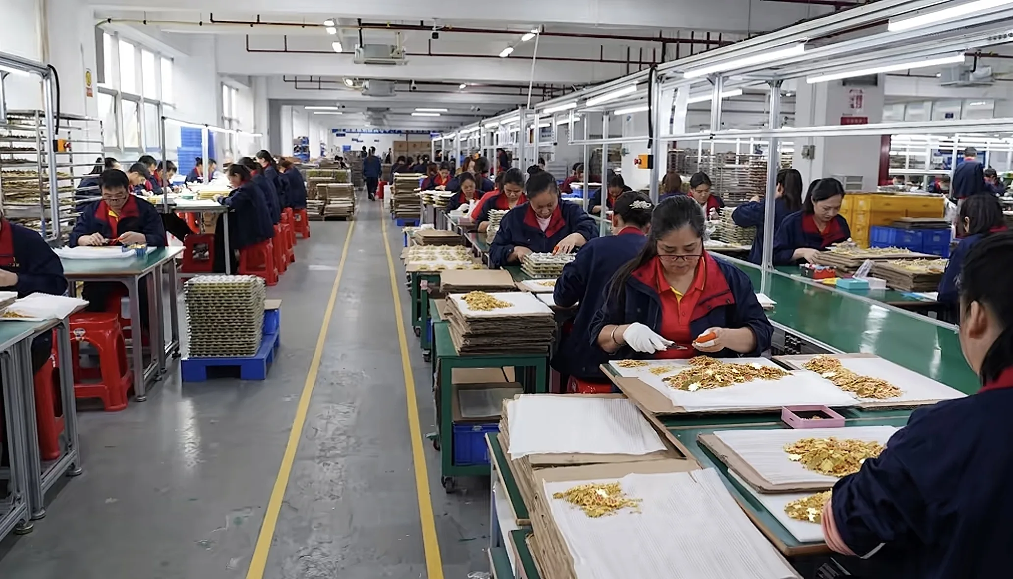 Custom souvenir manufacturing factory showing workers assembling and processing personalized souvenir products on a large-scale production line.