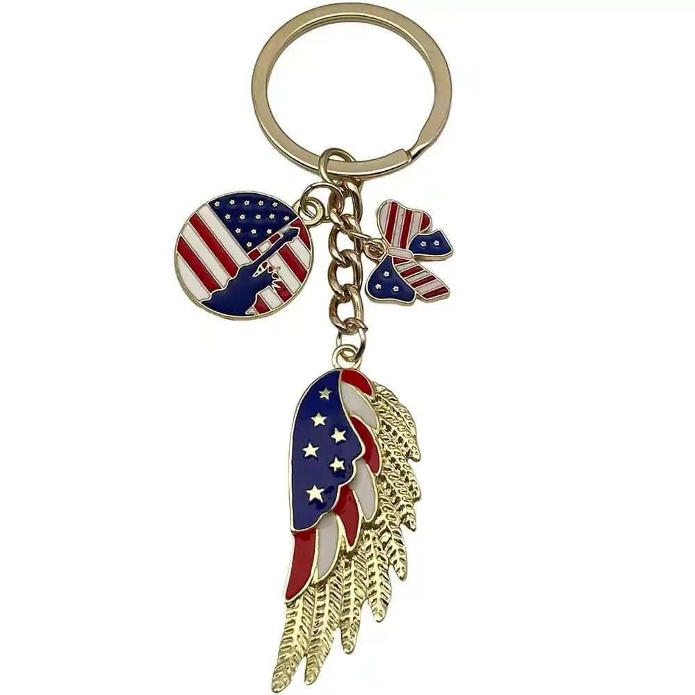 Gold-tone wing keychain with US flag enamel, a flag-patterned bow and round Statue of Liberty charm