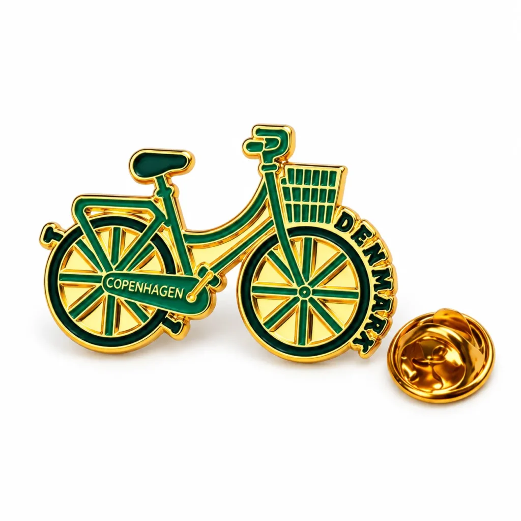 Green and gold-tone Copenhagen bicycle enamel pin with a front basket and butterfly clasp on a white background