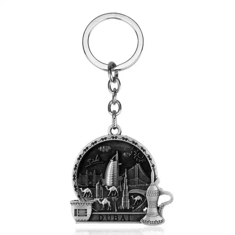 Silver-tone Dubai keychain with landmark relief, camels, a coffee cup and traditional coffee pot on a white background