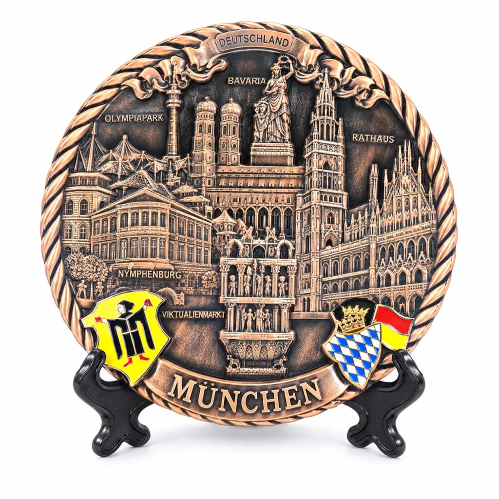 Copper-tone Munich souvenir plate with architectural relief, colored crests and MÜNCHEN lettering on a black stand