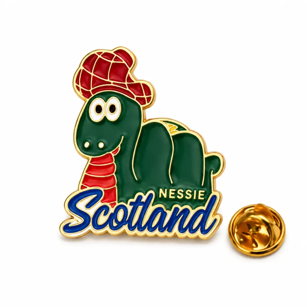 Green Scotland Nessie enamel pin wearing a red tartan hat, with a gold-tone butterfly clasp on a white background